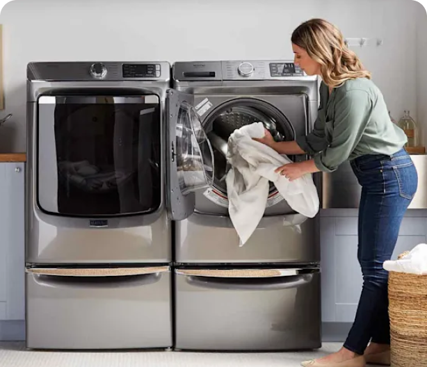Woman unloading laundry beside front-loading washer and dryer